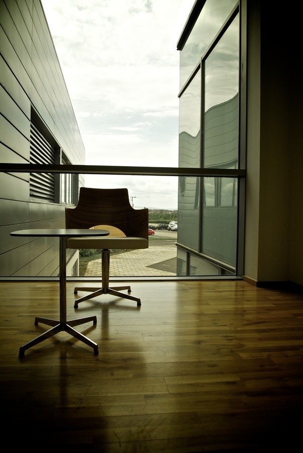 Table et fauteuil devant une baie vitrée, parquet net
